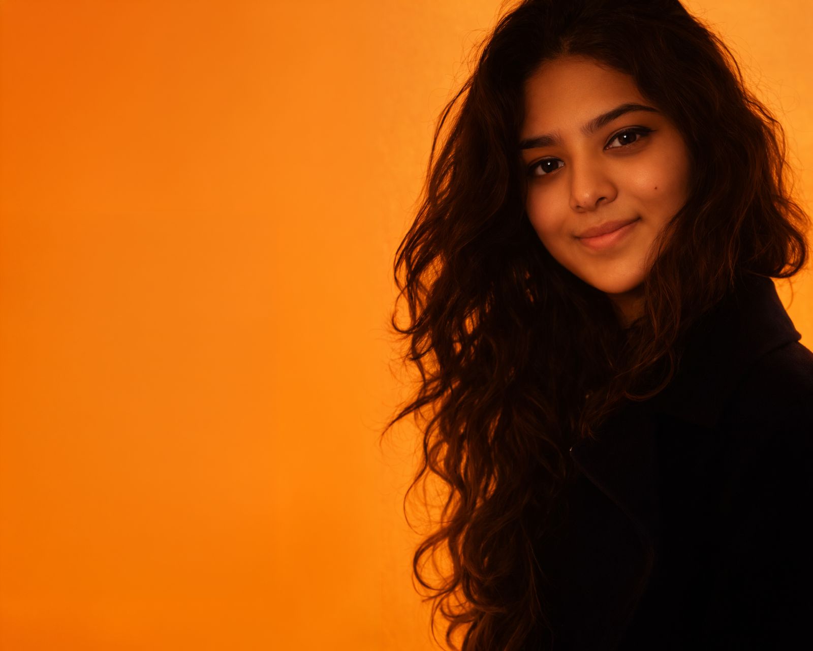 Tanya Jhaveri, founder of Anantam Designs and Anantam Site Manager, photographed against a warm orange backdrop
